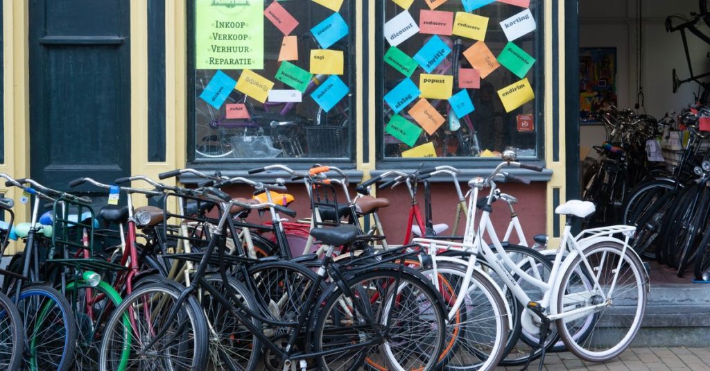 A bicycle shop exterior with various bikes and a colorful window display in an urban setting.