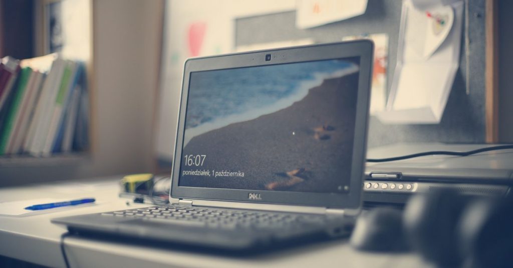 A contemporary workspace featuring a Dell laptop, books, and stationery on a desk, reflecting modern office essentials.
