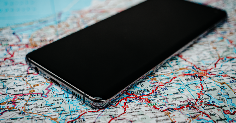 Close-up of a smartphone placed on a detailed road map of Poland, emphasizing travel and technology.
