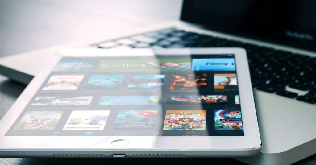 Tablet displaying streaming services on a laptop, illustrating digital entertainment setup.