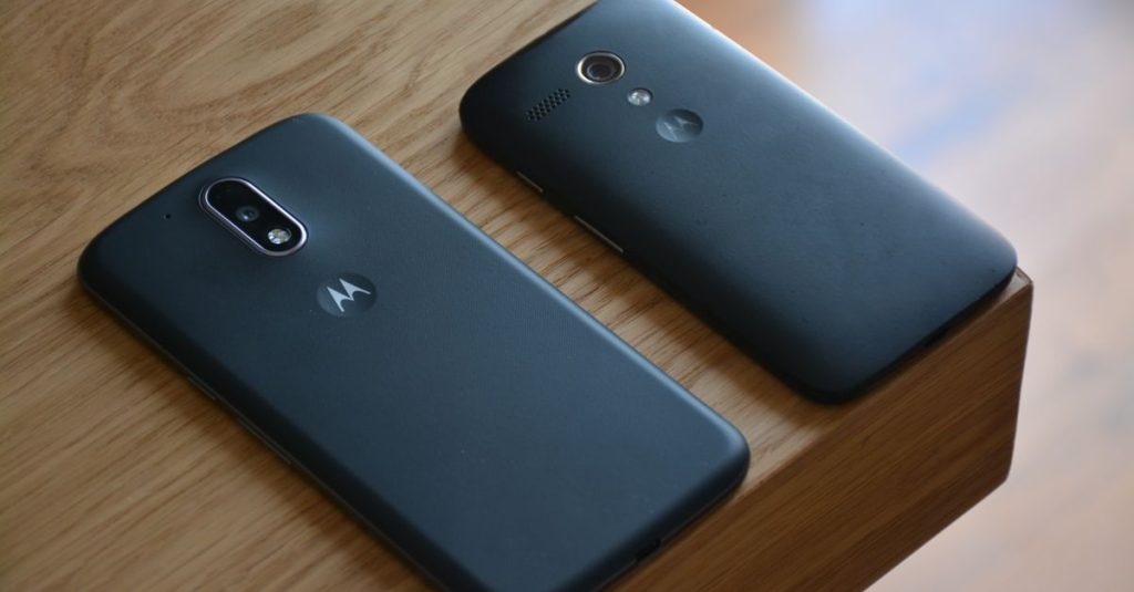 Two Motorola smartphones placed on a wooden table with natural lighting.