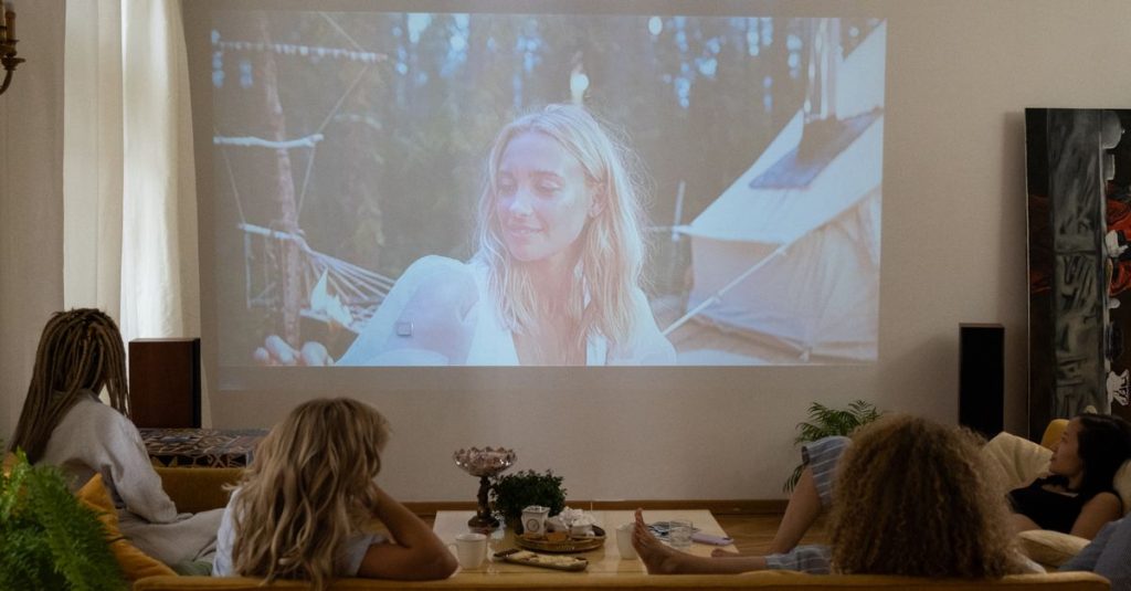 Group of women enjoying a movie night at home, projected on a screen in a cozy living room.