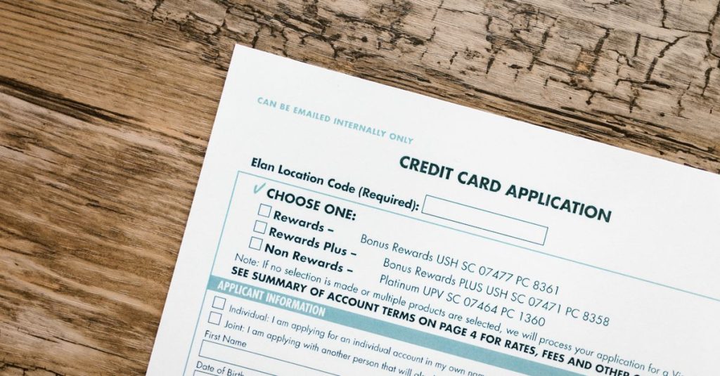 Top view of a credit card application form on rustic wooden background.