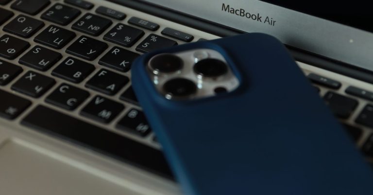 A close-up of a MacBook Air and an iPhone, showcasing modern technology in an office setting.