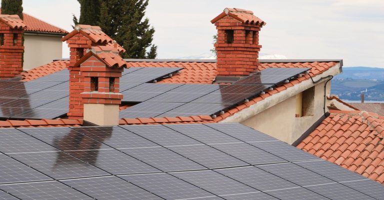 Solar panels on tiled roofs of houses with chimneys, capturing clean energy.