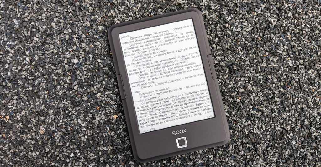 Digital BOOX e-book reader placed on a textured gravel surface, offering a tech contrast.