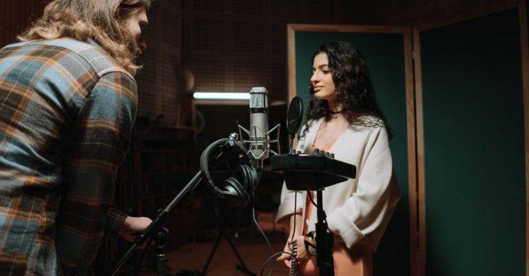 A woman recording vocals in a professional music studio setting.