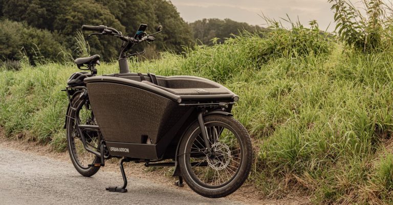 Vintage black cargo bike parked by grassy roadside in Düsseldorf, Germany.