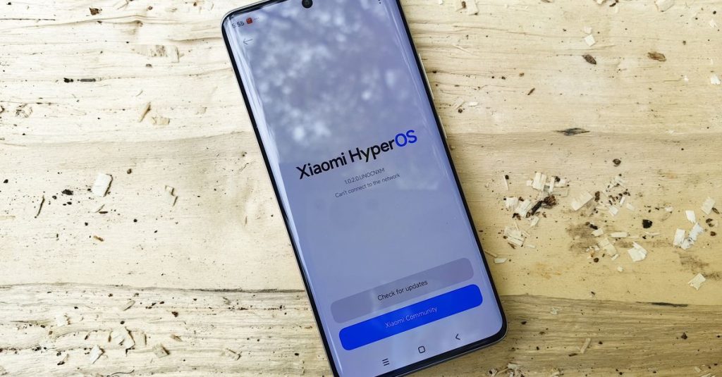Modern Xiaomi smartphone displaying HyperOS on a rustic wooden surface, showcasing technology innovation.