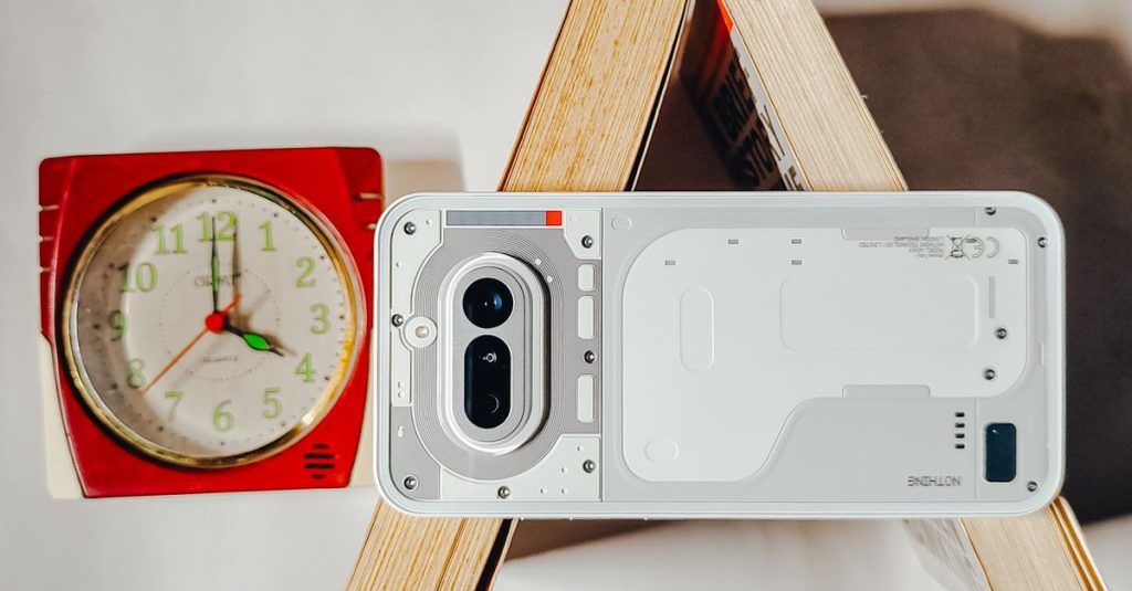 Artistic composition with a modern smartphone and vintage clock on books creating a unique flat lay design.